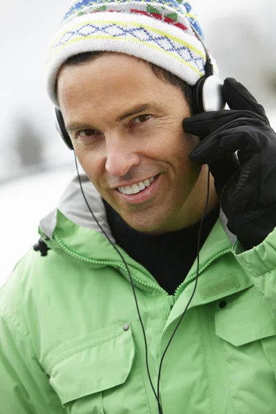 Mann trägt Kopfhörer und hört Musik im Winterkleid — Stockfoto