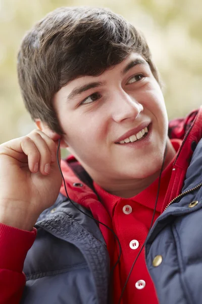 Adolescente niño usando auriculares y escuchando música usando ganar — Foto de Stock