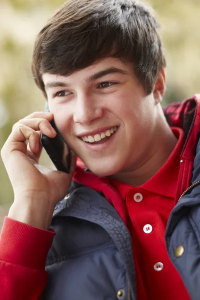Мальчик-подросток разговаривает по смартфону в зимней одежде — стоковое фото
