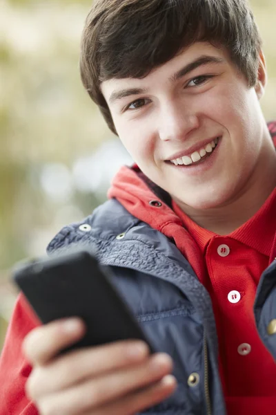 Tonårspojke textning på smartphone bär vinterkläder — Stockfoto