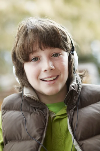 Chlapec sluchátka a poslech hudby na sobě zimní clo — Stock fotografie