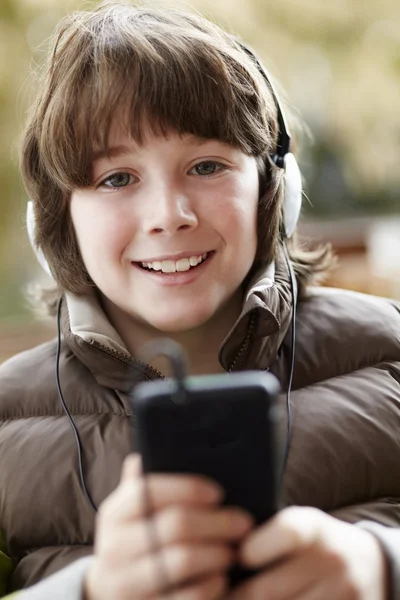 Chłopak sobie słuchawki i słuchanie muzyki na smartphone zużycie — Zdjęcie stockowe