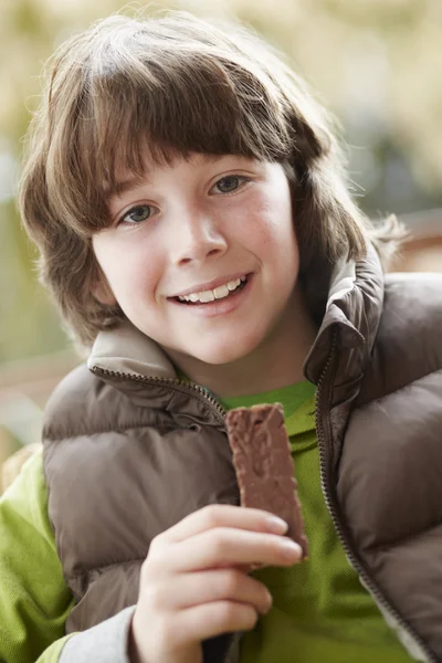 Pojken äta choklad bar bär vinterkläder — Stockfoto