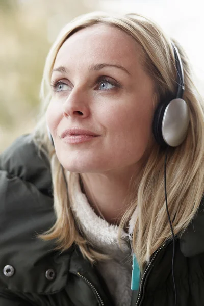 Žena nosit sluchátka a poslech hudby na sobě zimní c — Stock fotografie