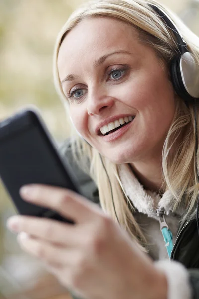 Frau trägt Kopfhörer und hört Musik auf dem Smartphone — Stockfoto
