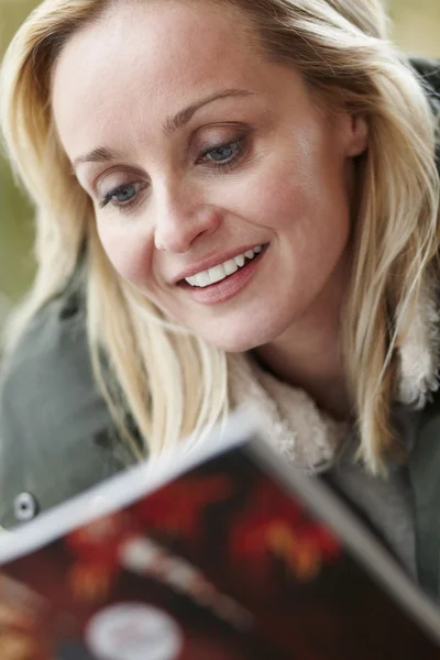 Zewnątrz portret kobiety noszenia ubrania zimowe czytanie magazin — Zdjęcie stockowe