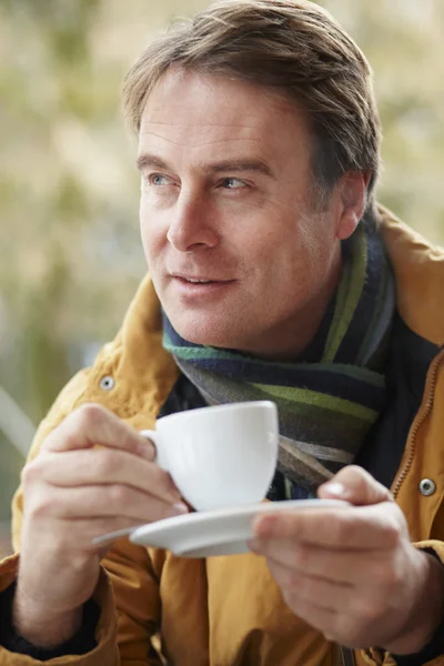Homem no café ao ar livre com bebida quente vestindo roupas de inverno — Fotografia de Stock