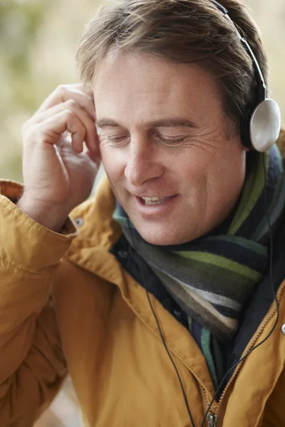 Mann trägt Kopfhörer und hört Musik im Winterkleid — Stockfoto