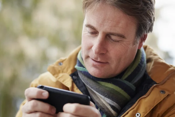Άνθρωπος γραπτών μηνυμάτων στο smartphone φορώντας ρούχα χειμώνα — Φωτογραφία Αρχείου