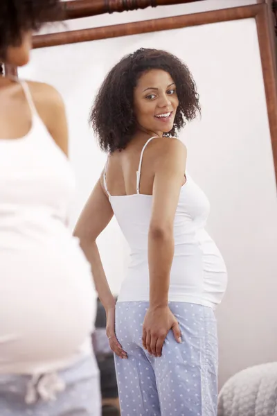 Pregnant woman looking in mirror Stock Image