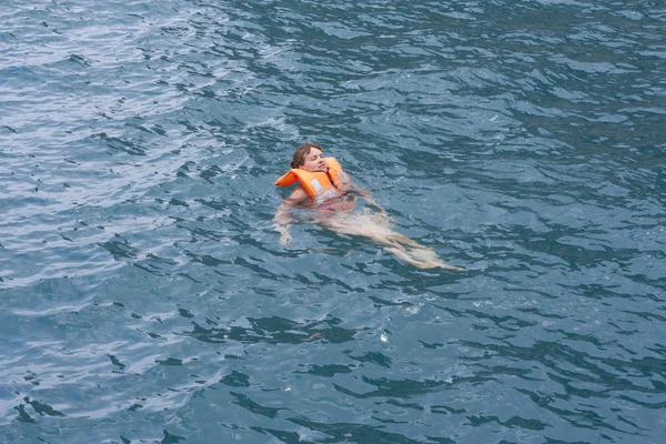 Frau in orangefarbener Schwimmweste im Wasser eines Meeres — Stockfoto