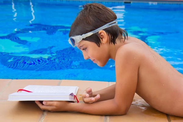 Menino lendo perto da piscina — Fotografia de Stock
