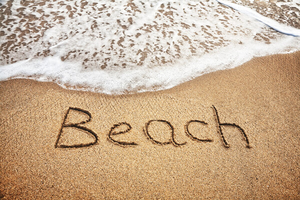 Beach word on the sand near the ocean