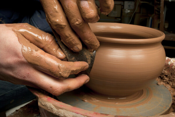 Hands of a potter, creating an earthen jar on the circle
