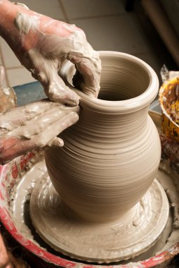 Hands of a potter, creating an earthen jar on the circle clipart