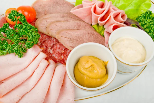 Cutting sausage and cured meat on a plate — Stock Photo, Image