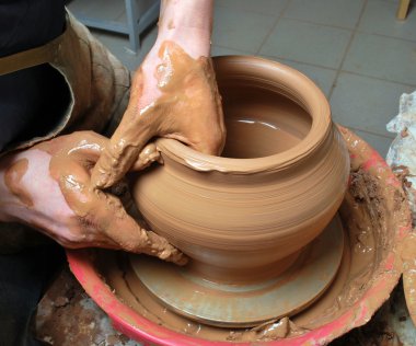 Hands of a potter, creating an earthen jar on the circle clipart