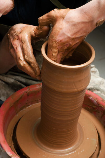 Руки гончара, создающего глиняную банку на круге