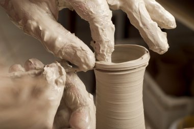 Bir çömlekçinin elleri, çemberin üzerinde toprak kavanozu yaratıyor.