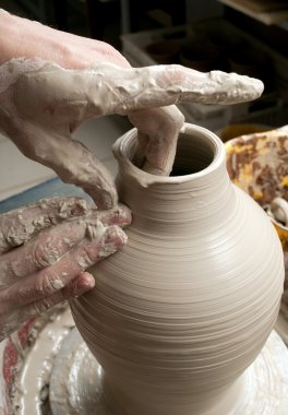 Hands of a potter, creating an earthen jar on the circle clipart