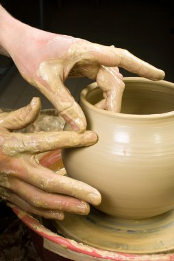 Hands of a potter, creating an earthen jar of white clay clipart