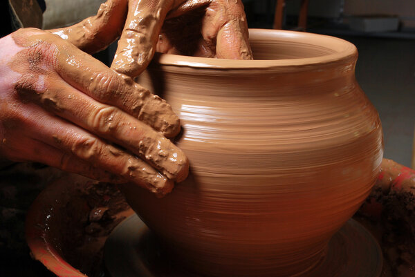 Руки гончара, создающего глиняную банку на круге