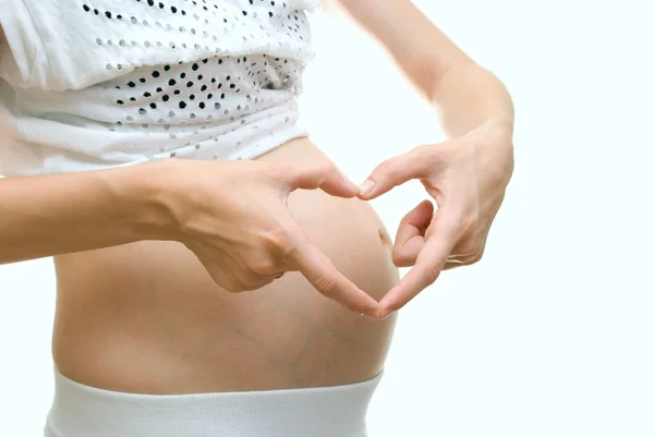 Mujer embarazada haciendo forma de corazón con las manos —  Fotos de Stock