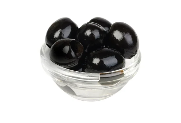 Azeitonas pretas sem caroço em vidro isoladas na macro branca — Fotografia de Stock