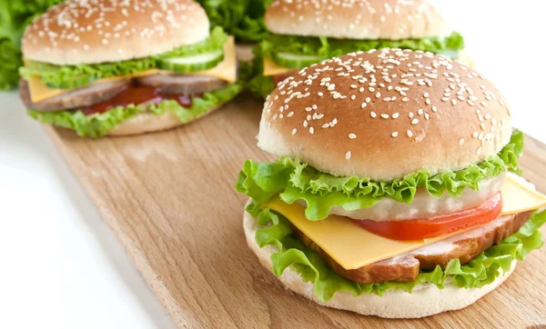 Tres hamburguesas con carne y verduras en plato de madera — Foto de Stock
