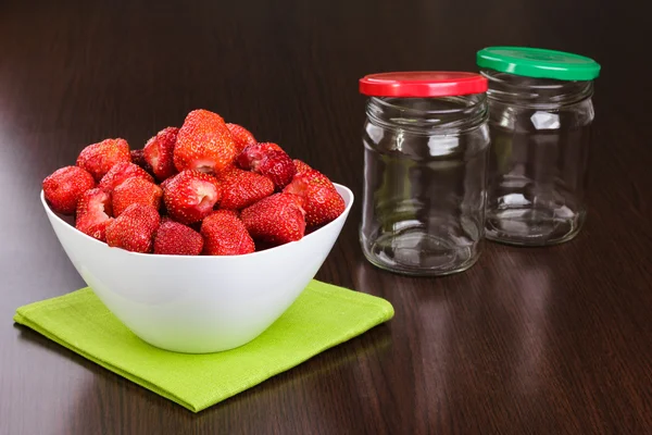 Strawberry cleared in a white bowl and empty jars with covers for house conservation Stock Photo