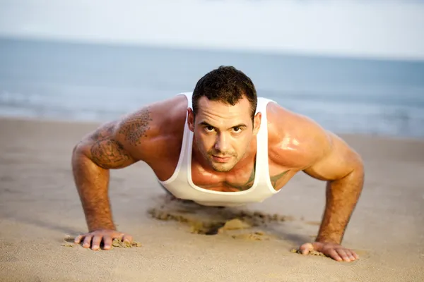 Άνθρωπος που κάνει την ώθηση ups σε μια παραλία — Φωτογραφία Αρχείου