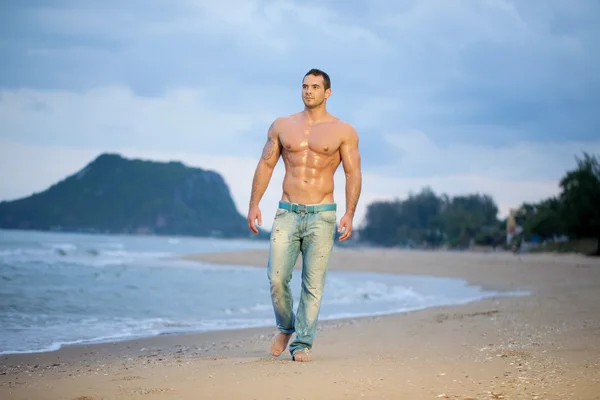 Musculoso macho caminando a lo largo de una playa — Foto de Stock