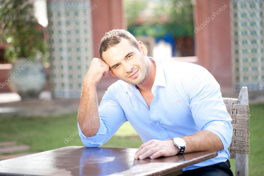 Smiling man seated at a table outdoors