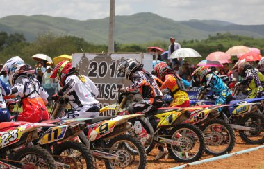 Motocross riders lined up at the start gate clipart