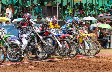 Motocross riders lined up at the start gate clipart