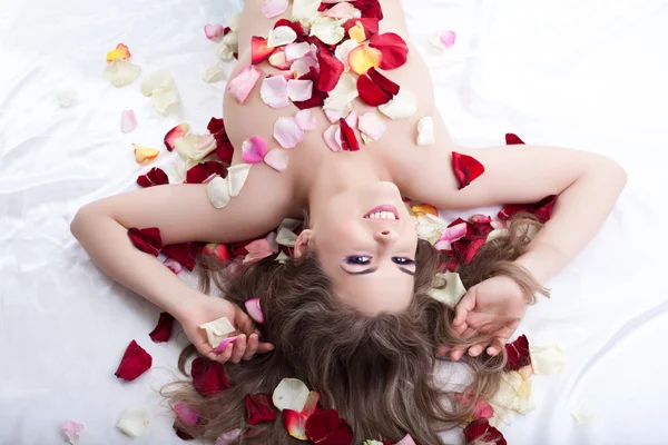 在玫瑰花瓣中的年轻女子 — 图库照片