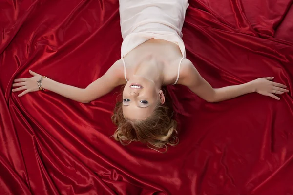 Bardzo młoda kobieta, leżąc na jedwabiu arkuszy — Zdjęcie stockowe