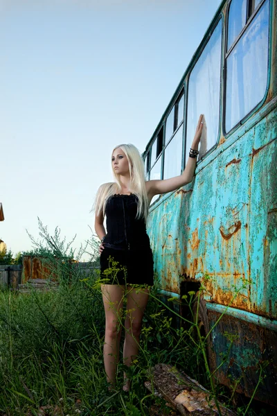 Bionda donna in piedi vicino abbandonato autobus — Foto Stock