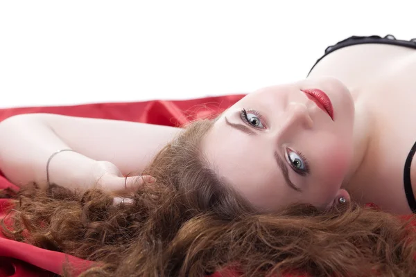 Женщина лежит на красной простыне — стоковое фото