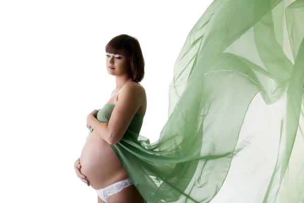 Krásná těhotná žena s zelenou foukání tkanina — Stock fotografie