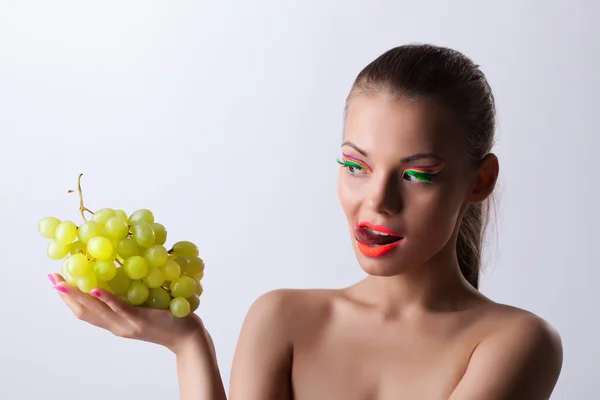 Hauska nainen hehku meikki ja vihreä viinirypäleet — kuvapankkivalokuva