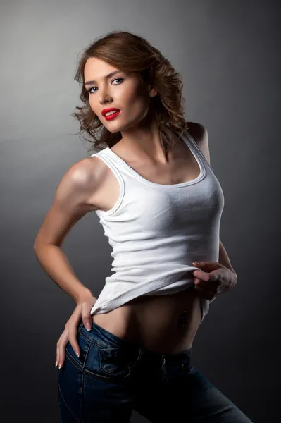 Kobieta uroda pozowanie dżinsy i biały tank top — Zdjęcie stockowe