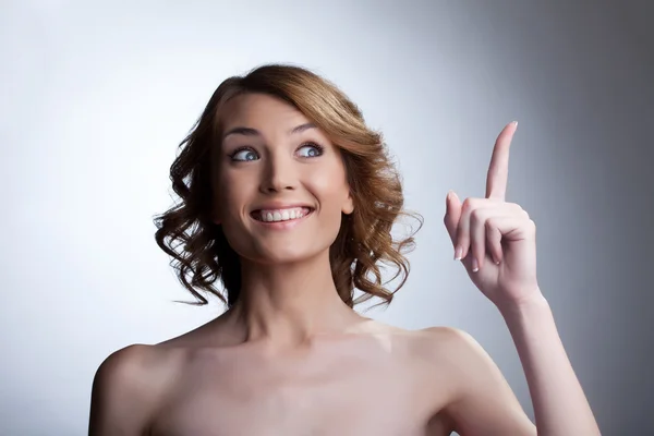 Hübsche junge Frau zeigt mit dem Finger und lächelt — Stockfoto