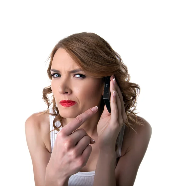 Молодая женщина указывает на мобильный телефон с подозрением — стоковое фото