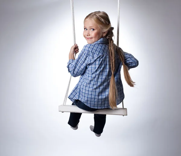 Söt flicka sitter på swing — Stockfoto