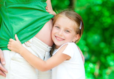 Girl hugging mother's belly clipart