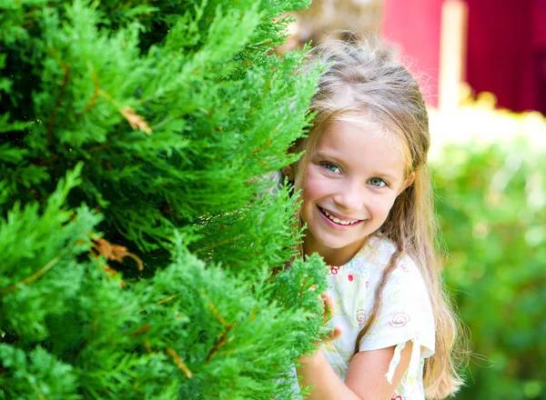 Menina olha atrás de uma árvore — Fotografia de Stock