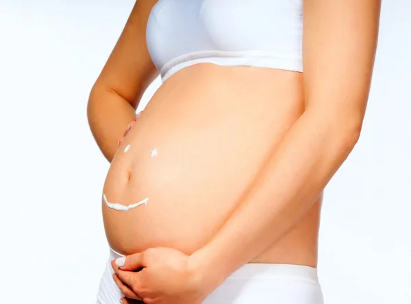 Schwangere junge Frau mit kosmetischer Creme — Stockfoto