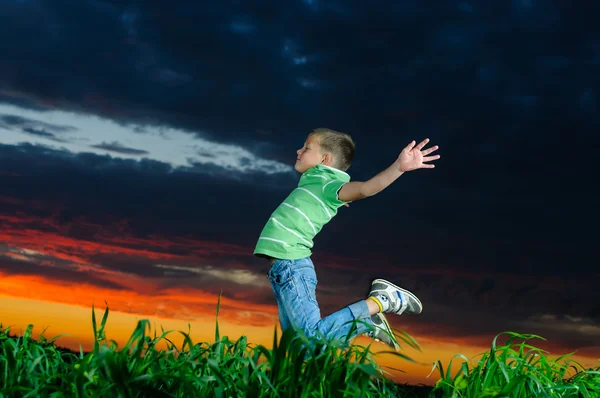 Photo of young boy jumping and raising hands in outside — Stock Photo, Image