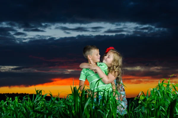 Grupo de crianças felizes brincando no prado, pôr do sol, horário de verão — Fotografia de Stock